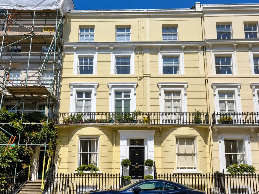 Cream townhouse exterior with white window surrounds and black railings